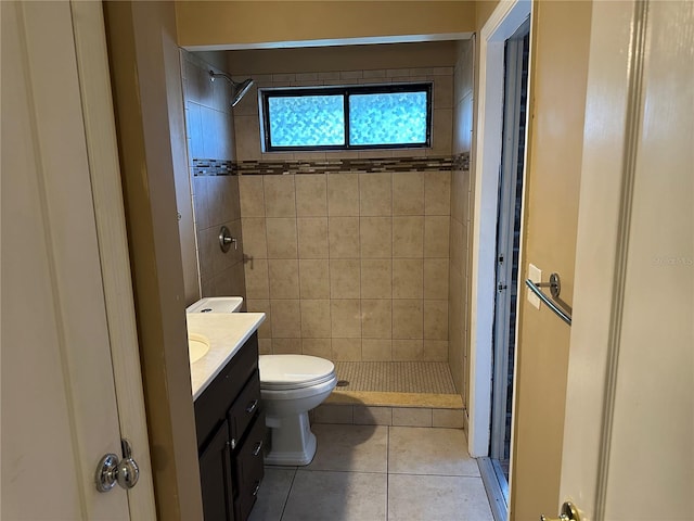 bathroom with vanity, a tile shower, toilet, and tile patterned flooring