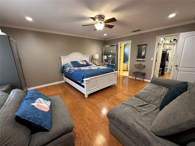 bedroom with a closet, a spacious closet, hardwood / wood-style floors, crown molding, and ceiling fan