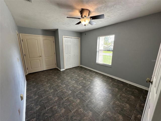 unfurnished bedroom with ceiling fan and a textured ceiling