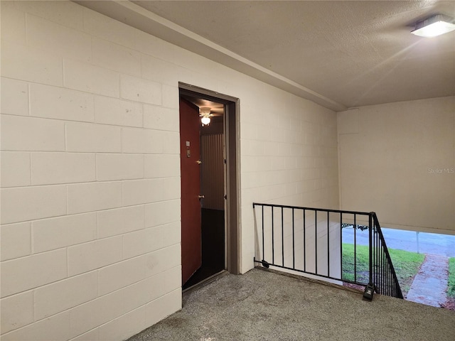 hallway with a textured ceiling and concrete block wall