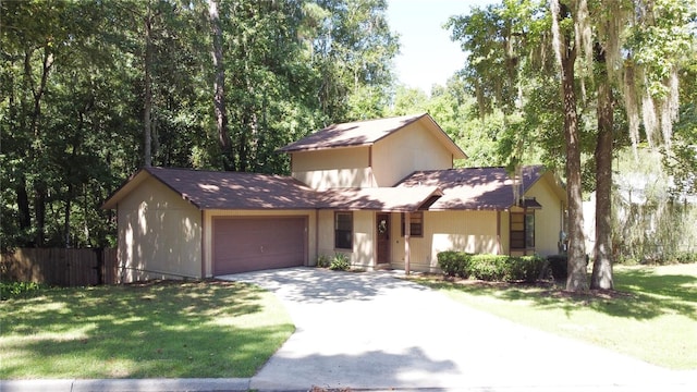 view of front facade with a front yard, fence, driveway, and an attached garage