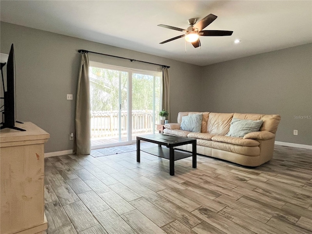 living area with a ceiling fan, baseboards, and wood finished floors