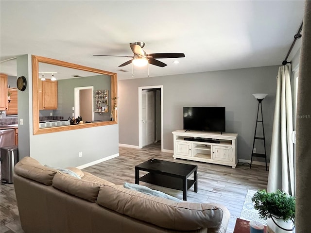 living area featuring wood finished floors, a ceiling fan, and baseboards