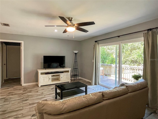 living room with light wood-style floors, visible vents, ceiling fan, and baseboards