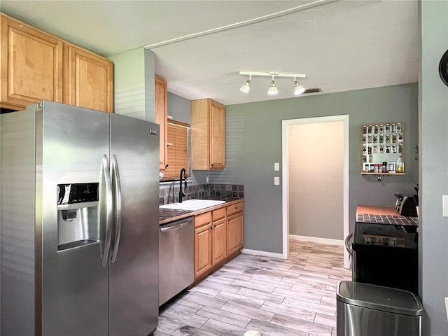 kitchen with a sink, baseboards, appliances with stainless steel finishes, wood tiled floor, and light brown cabinetry