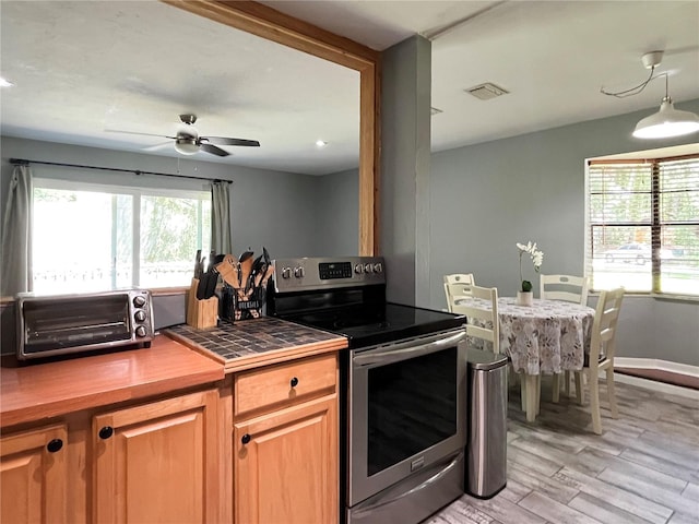 kitchen with a toaster, visible vents, tile counters, stainless steel electric stove, and light wood-type flooring