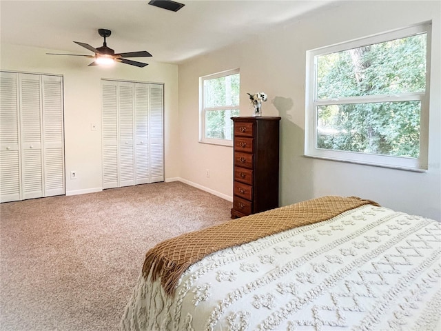 bedroom with carpet floors, a ceiling fan, baseboards, and two closets