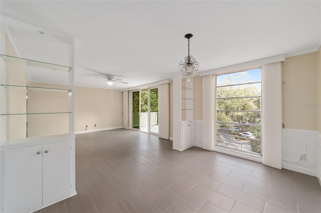 tiled spare room with a healthy amount of sunlight and ceiling fan with notable chandelier