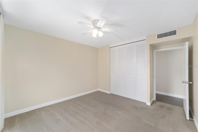 unfurnished bedroom featuring a closet, light colored carpet, and ceiling fan