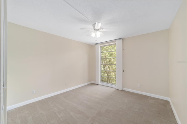 carpeted spare room featuring ceiling fan and a textured ceiling