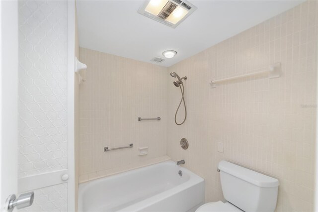 bathroom featuring tiled shower / bath combo, tile walls, and toilet