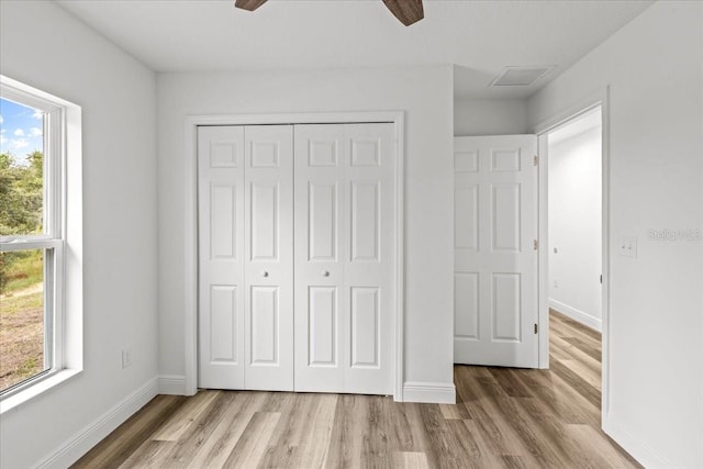 unfurnished bedroom with multiple windows, light hardwood / wood-style flooring, a closet, and ceiling fan