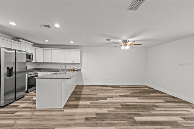 kitchen featuring kitchen peninsula, stainless steel appliances, ceiling fan, sink, and white cabinetry