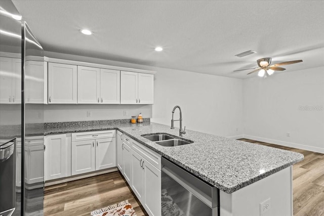 kitchen featuring ceiling fan, sink, kitchen peninsula, wood-type flooring, and white cabinets