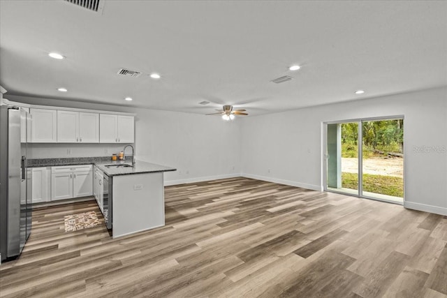 kitchen with white cabinetry, sink, ceiling fan, stainless steel refrigerator with ice dispenser, and kitchen peninsula