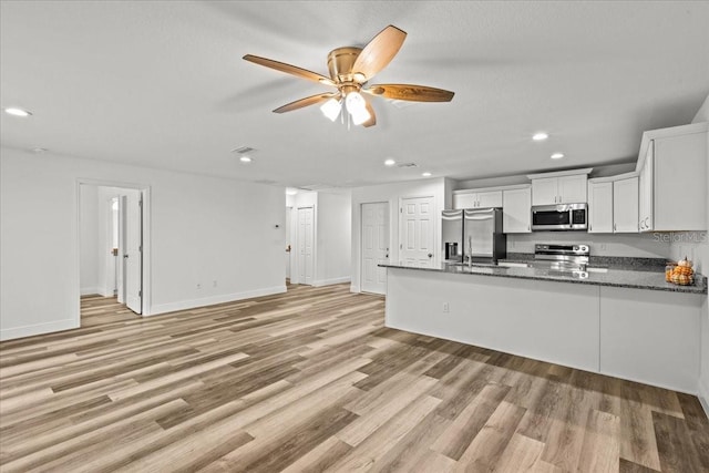 kitchen with kitchen peninsula, light wood-type flooring, stainless steel appliances, and white cabinets