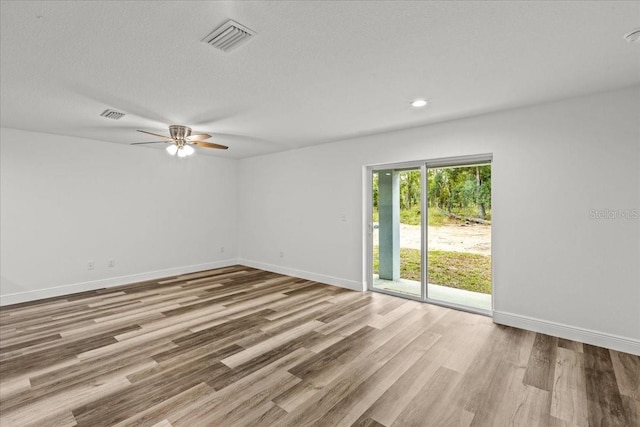 empty room with ceiling fan, light hardwood / wood-style flooring, and a textured ceiling