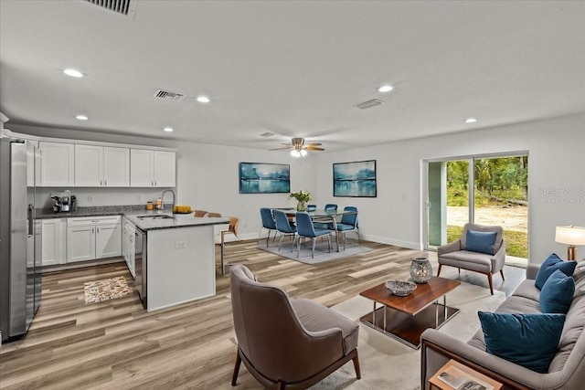 living room with light hardwood / wood-style flooring, ceiling fan, and sink