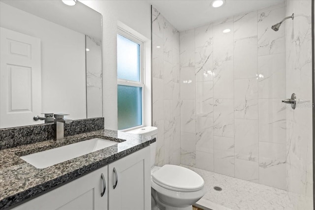 bathroom with tiled shower, vanity, and toilet