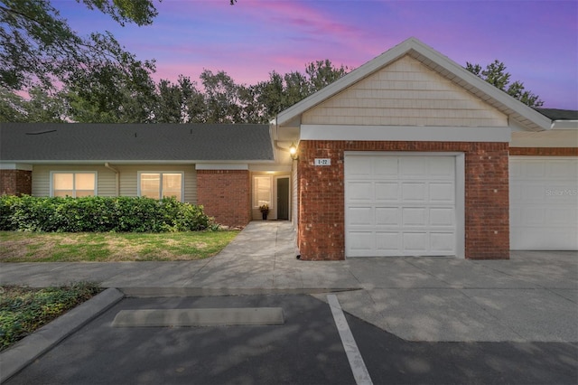 single story home featuring a garage and brick siding