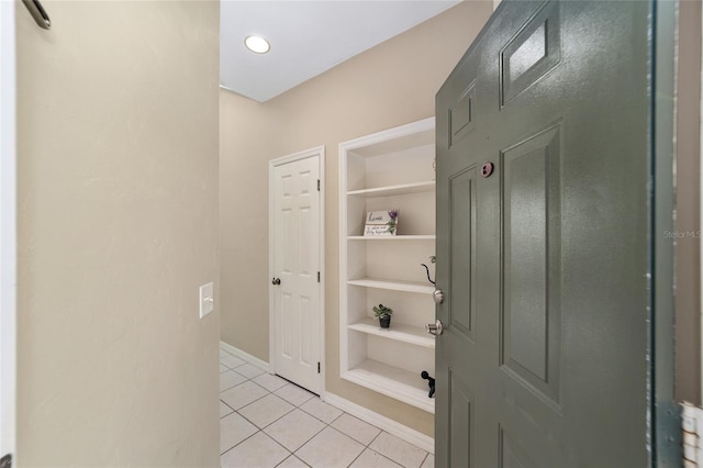 hall with built in shelves and light tile patterned flooring