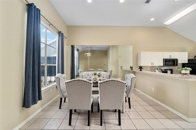 tiled dining area featuring vaulted ceiling and sink