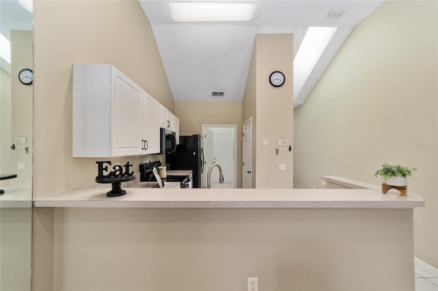 kitchen featuring visible vents, stainless steel microwave, electric range, white cabinets, and a peninsula