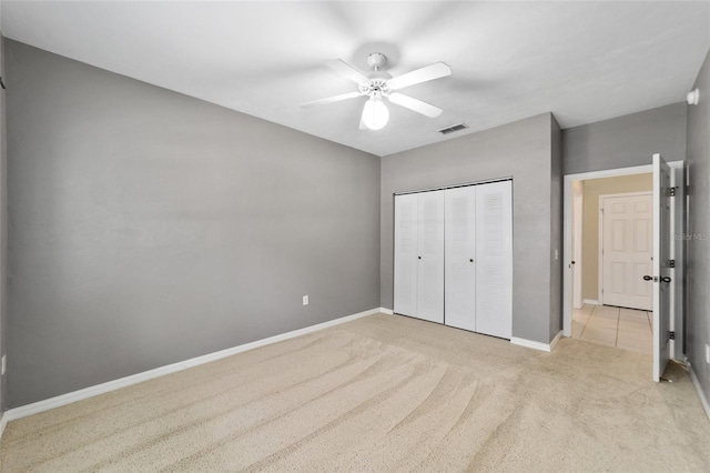 unfurnished bedroom featuring a closet, ceiling fan, and light colored carpet