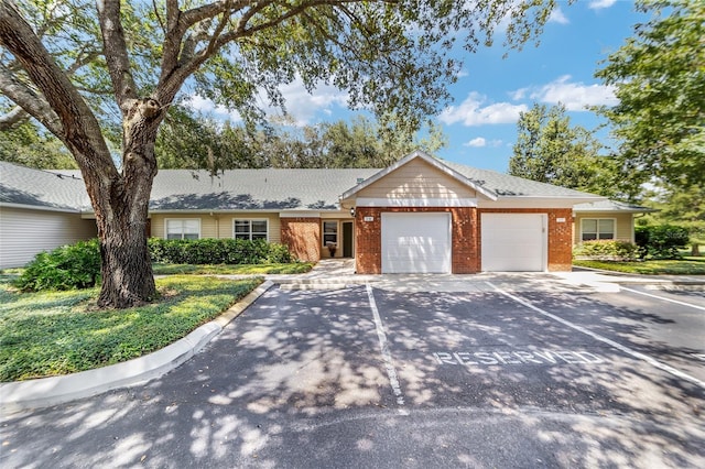 single story home with driveway, brick siding, and an attached garage