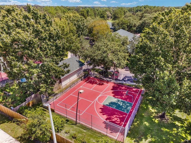 view of basketball court with community basketball court, fence, and a view of trees