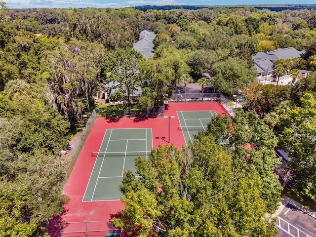 view of tennis court featuring fence and a wooded view