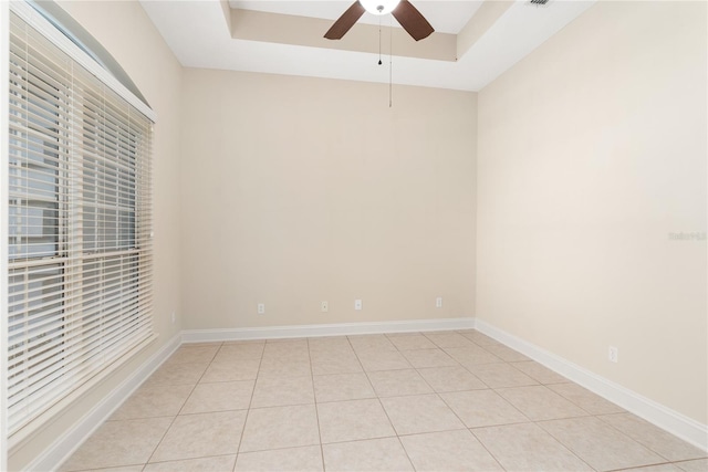 spare room featuring a tray ceiling, light tile patterned floors, and ceiling fan