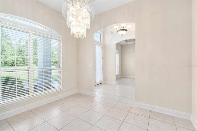 empty room with light tile patterned floors and a chandelier