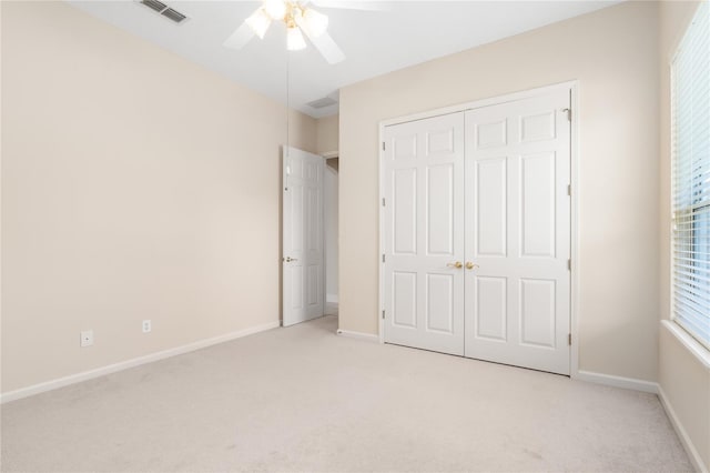 unfurnished bedroom with light colored carpet, ceiling fan, and a closet