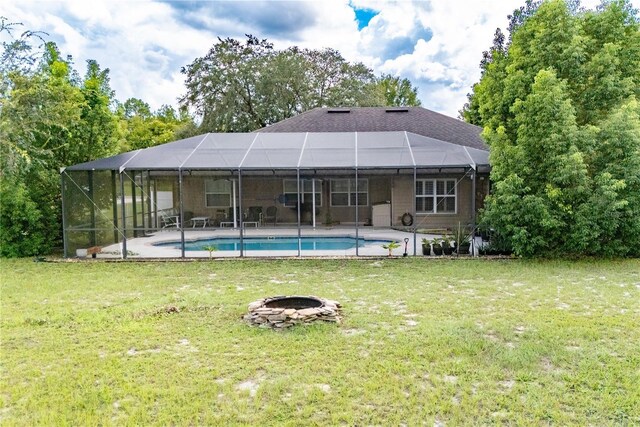 rear view of property featuring glass enclosure and a lawn