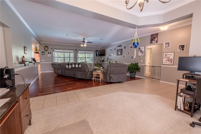 living room featuring ceiling fan with notable chandelier, ornamental molding, and light hardwood / wood-style flooring