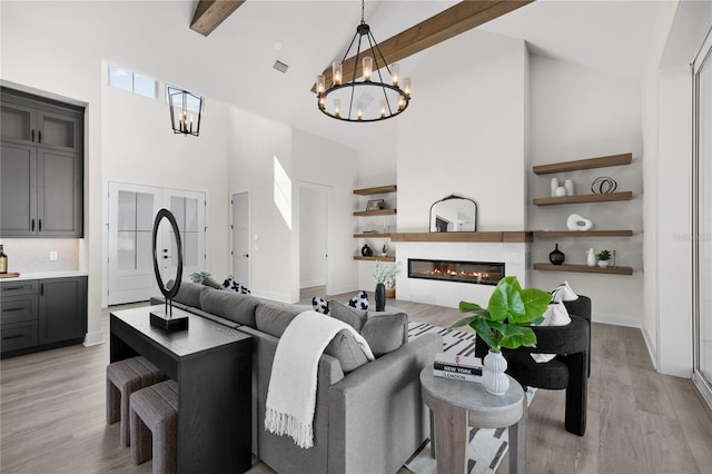 1101 SW 136th St, Newberry, FL 32669 - living area with high vaulted ceiling, a glass covered fireplace, an inviting chandelier, beamed ceiling, and light wood-style flooring