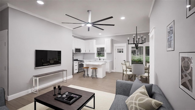 living room with ceiling fan with notable chandelier, light hardwood / wood-style flooring, and ornamental molding