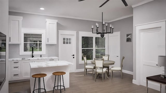 kitchen with ceiling fan with notable chandelier, white cabinets, hardwood / wood-style floors, and a kitchen island