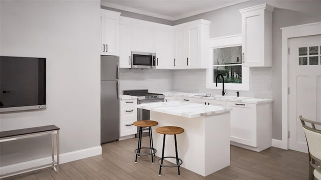 kitchen featuring appliances with stainless steel finishes, white cabinetry, a breakfast bar, a kitchen island, and light wood-type flooring