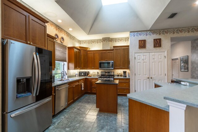 kitchen featuring stainless steel appliances, lofted ceiling, a kitchen island, and sink