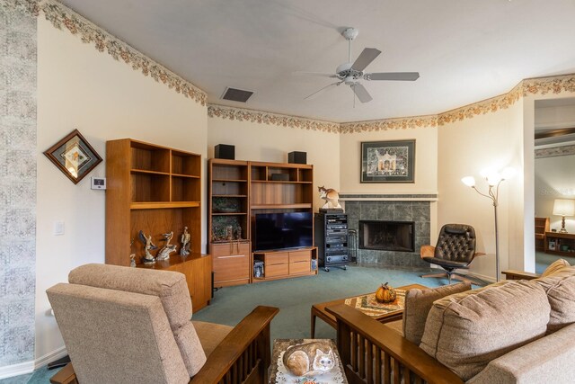 carpeted living room featuring ceiling fan and a tiled fireplace