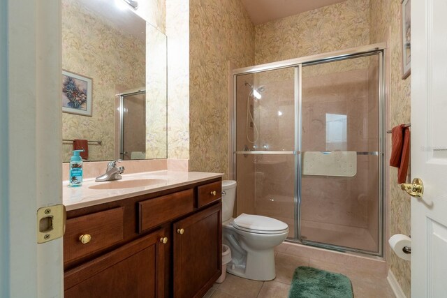 bathroom featuring a shower with door, toilet, vanity, and tile patterned flooring