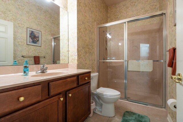 bathroom featuring a shower with door, tile patterned floors, toilet, and vanity