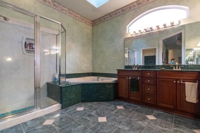 bathroom featuring a skylight, tile patterned flooring, separate shower and tub, and vanity