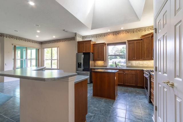 11509 NW 67th Ter, Alachua, FL 32615 - kitchen featuring appliances with stainless steel finishes, a healthy amount of sunlight, a kitchen island, and brown cabinetry