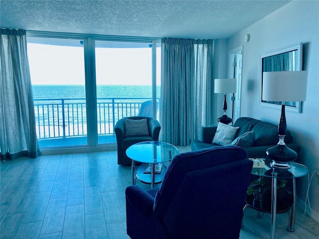 living room featuring a textured ceiling, light hardwood / wood-style flooring, and a water view