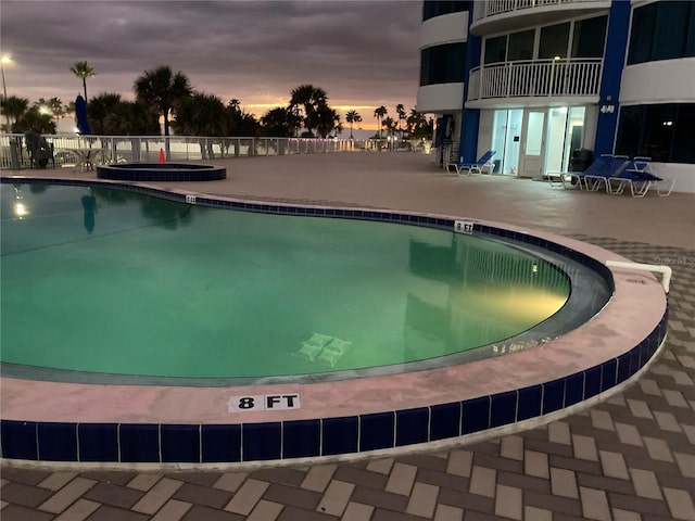 pool at dusk featuring a patio