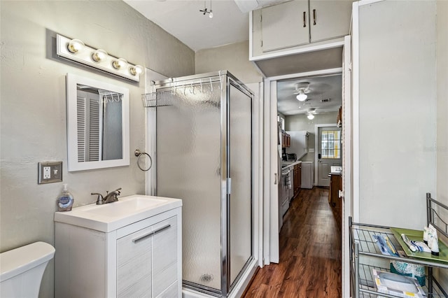 full bath featuring toilet, a ceiling fan, a stall shower, vanity, and wood finished floors