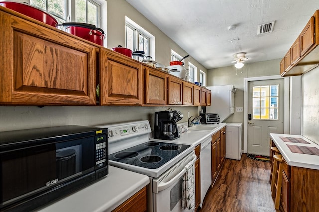 kitchen with white appliances, brown cabinetry, dark wood finished floors, and visible vents